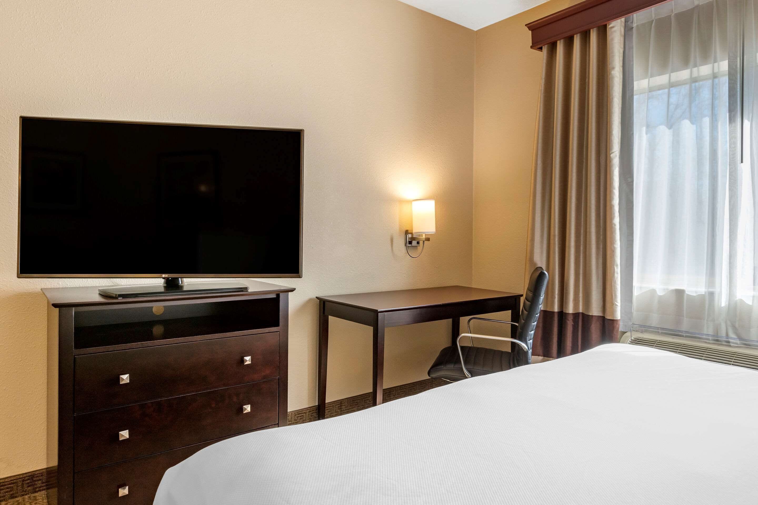 A hotel room with a large bed, a flat-screen TV, a desk, and a chair.