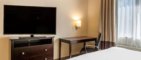 A hotel room with a large bed, a flat-screen TV, a desk, and a chair.