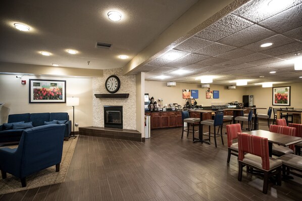 A spacious lobby with a fireplace, a dining area with red upholstered booths, and a kitchen area.