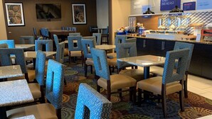 A hotel dining area with tables and chairs, a buffet counter, and a patterned carpet. - Holiday Inn Express St Paul S - Inver Grove Hgts by IHG (Inver Grove Heights)