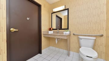 A bathroom with a toilet, sink, mirror, and a door.