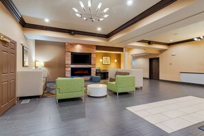A lobby with a fireplace, seating area, and a modern ceiling design. - Holiday Inn Express St Paul S - Inver Grove Hgts by IHG (Inver Grove Heights)