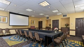 A conference room with a long table, chairs, a projector screen, and a carpeted floor. - Holiday Inn Express St Paul S - Inver Grove Hgts by IHG (Inver Grove Heights)