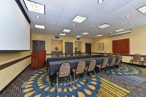 A conference room with a long table, chairs, a projector screen, and a carpeted floor. - Holiday Inn Express St Paul S - Inver Grove Hgts by IHG (Inver Grove Heights)