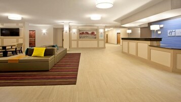 Un amplio vestíbulo de hotel con mostrador de recepción, zona de estar y televisor de pantalla plana.