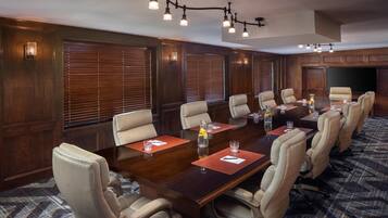 A conference room with a long table, multiple chairs, and a large screen.
