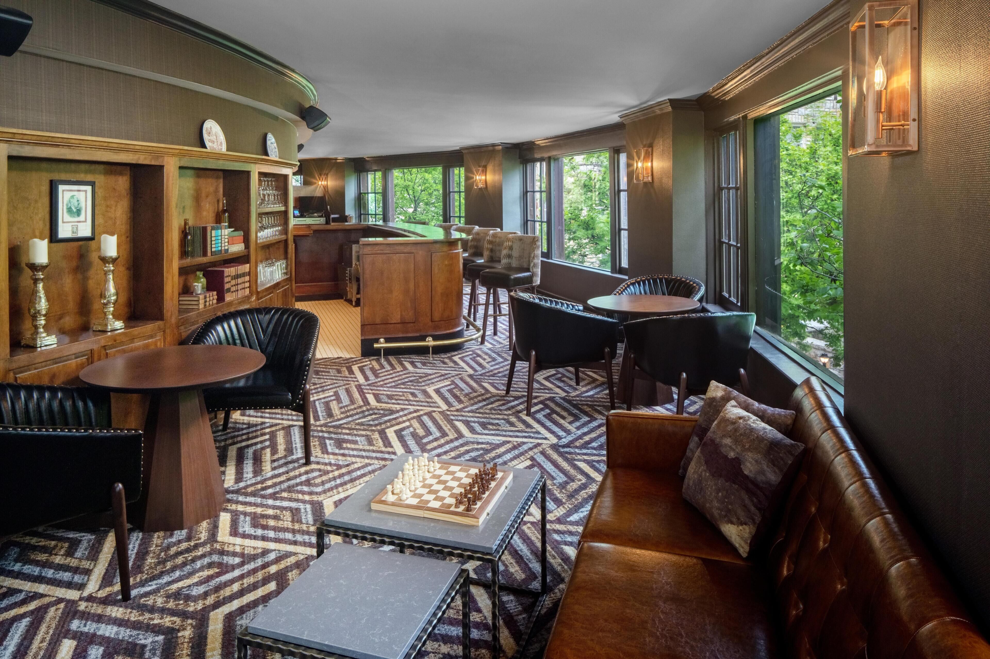 A cozy interior with a billiards table, leather seating, and a chessboard.