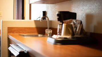 Una cocina con encimera de madera, un lavamanos de acero inoxidable y una cafetera.