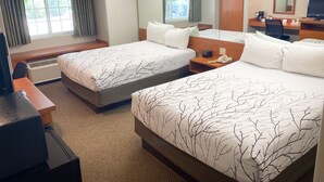 Habitación de hotel con dos camas, un escritorio, una silla, un calentador, un teléfono y un espejo.