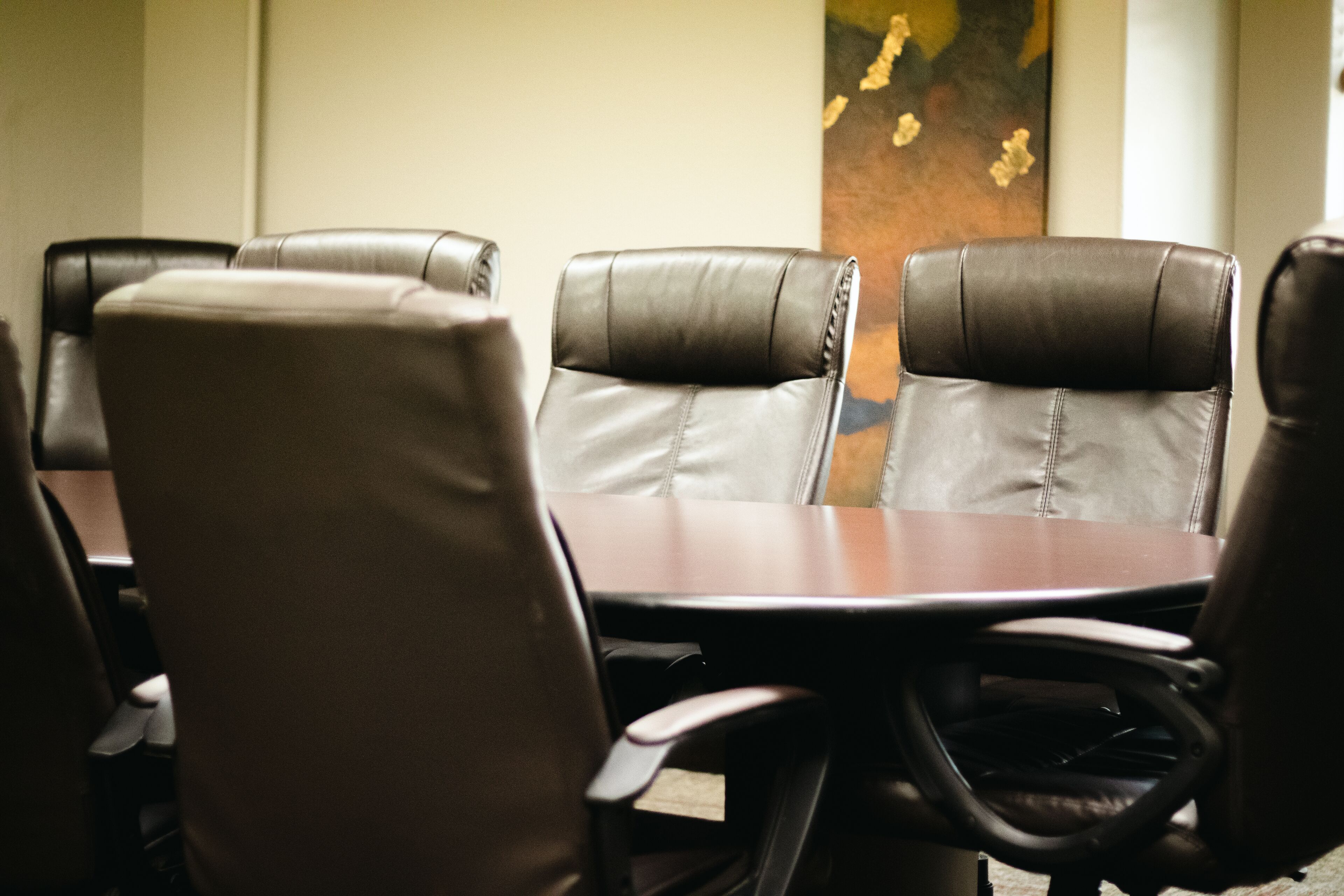 Una sala de conferencias con sillas de cuero y una mesa de madera.