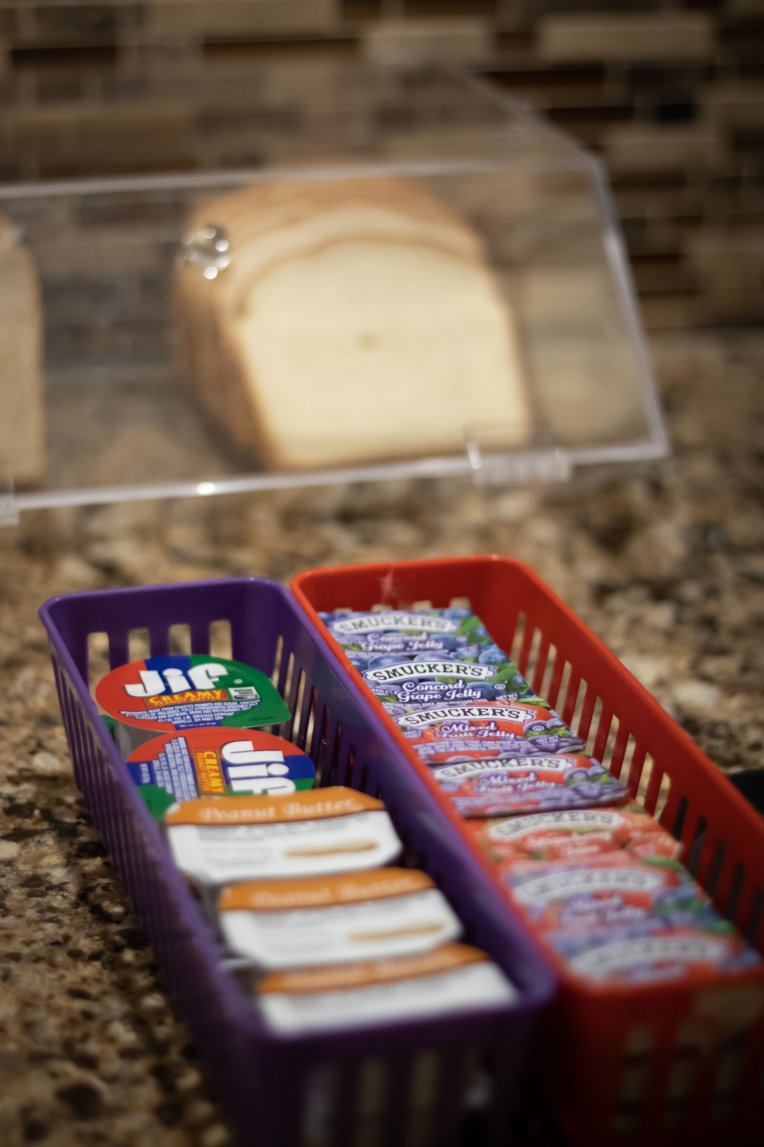 Two baskets containing various packaged snacks on a granite countertop.