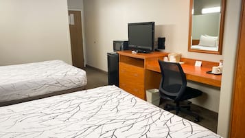 A hotel room with two beds, a desk with a computer, a chair, and a mirror.