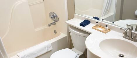 A bathroom with a bathtub, toilet, sink, and mirror.