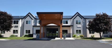 A modern building with a covered entrance, multiple windows, and a parking lot.