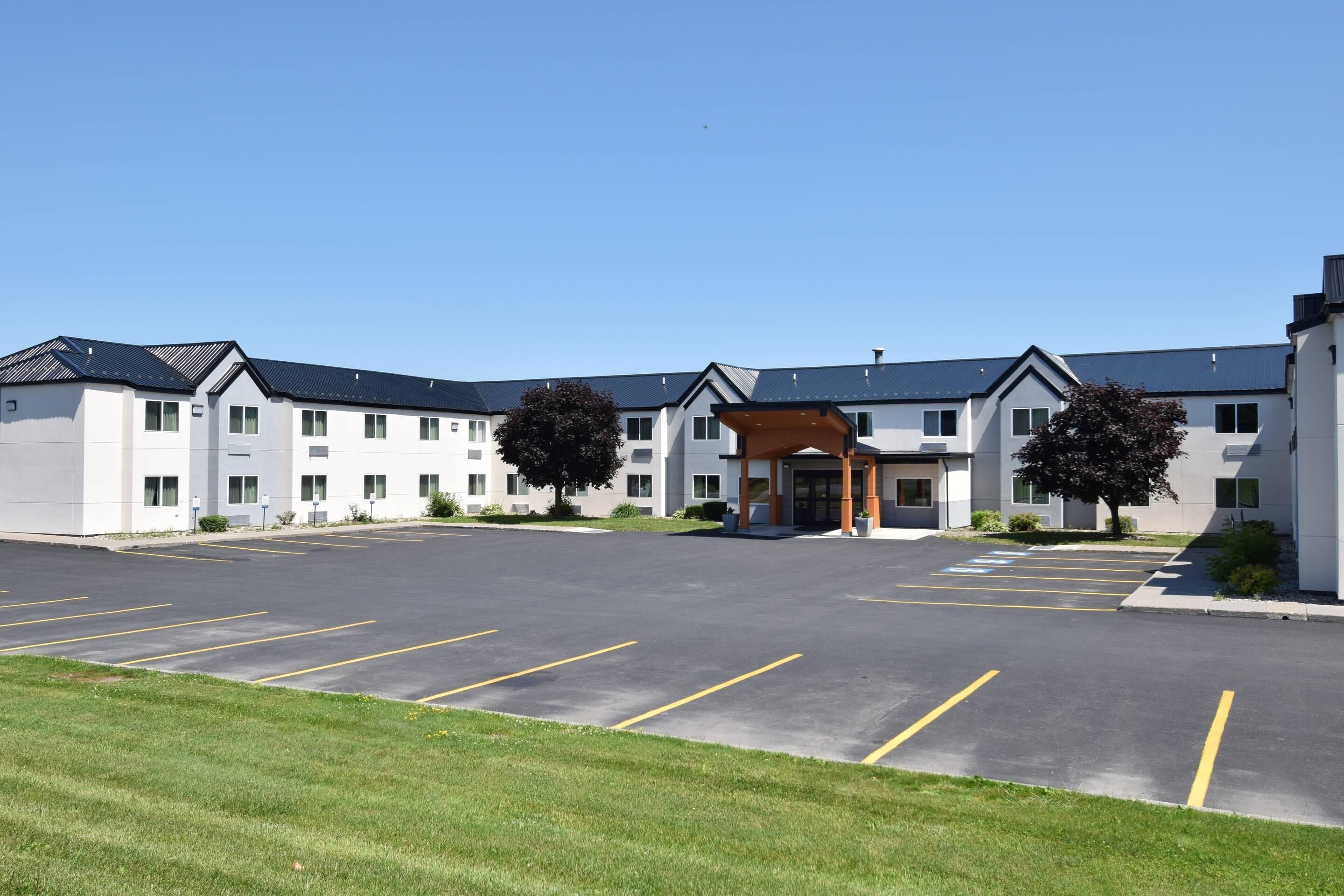 Un hôtel moderne doté d’une entrée centrale, de nombreux espaces de stationnement et d’une pelouse bien entretenue.