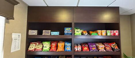 A snack display with various packaged snacks and a menu on the wall.