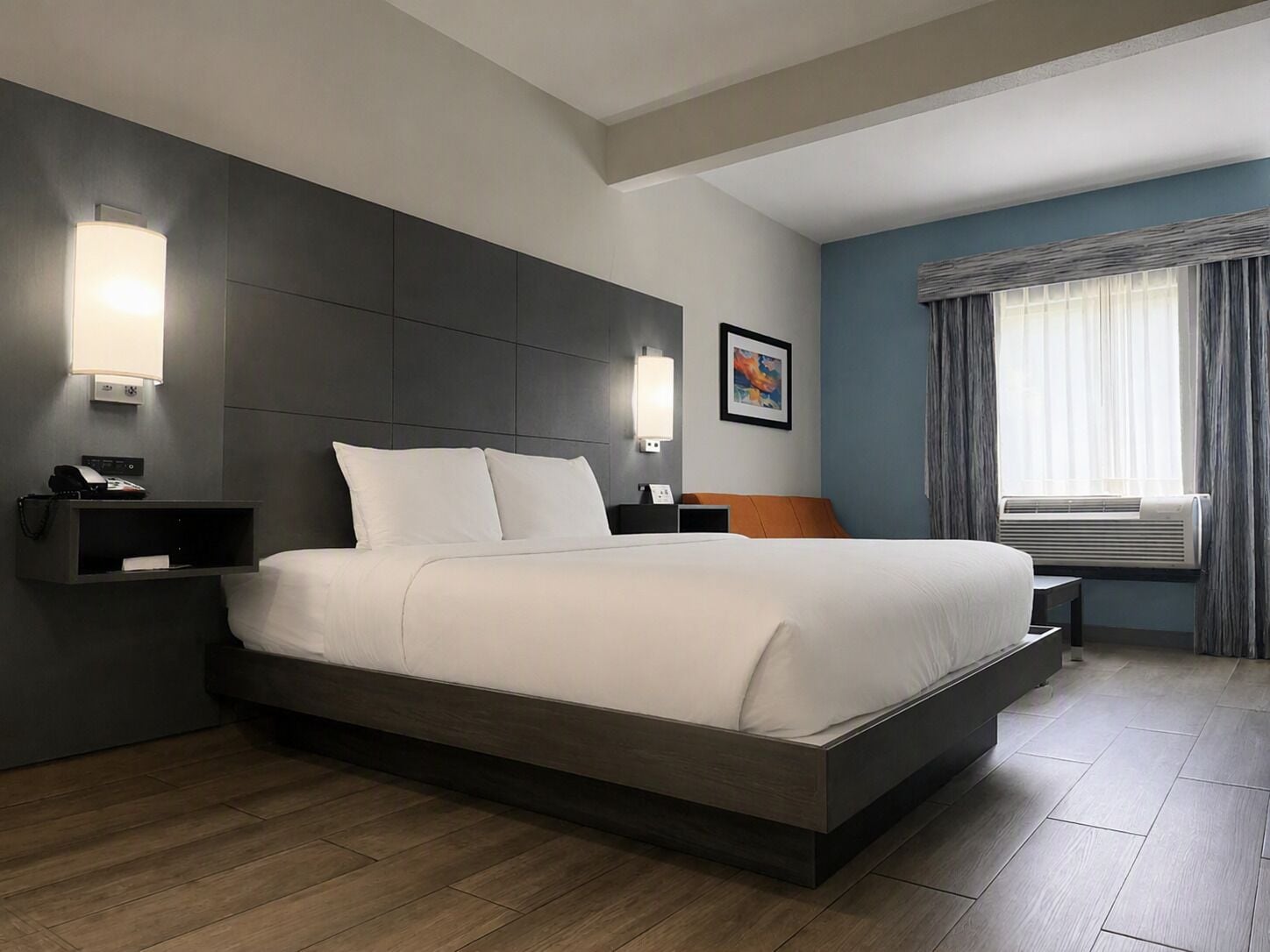 A modern hotel room with a large bed, bedside tables, a wall-mounted phone, and a window with curtains.