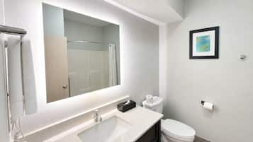 Un baño moderno con un espejo grande, un lavamanos, un inodoro y una ducha.