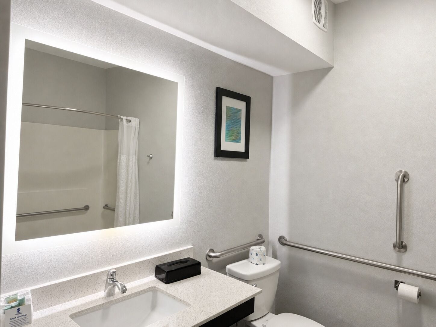 Une salle de bain avec un lavabo blanc, un miroir, des toilettes et un espace douche.