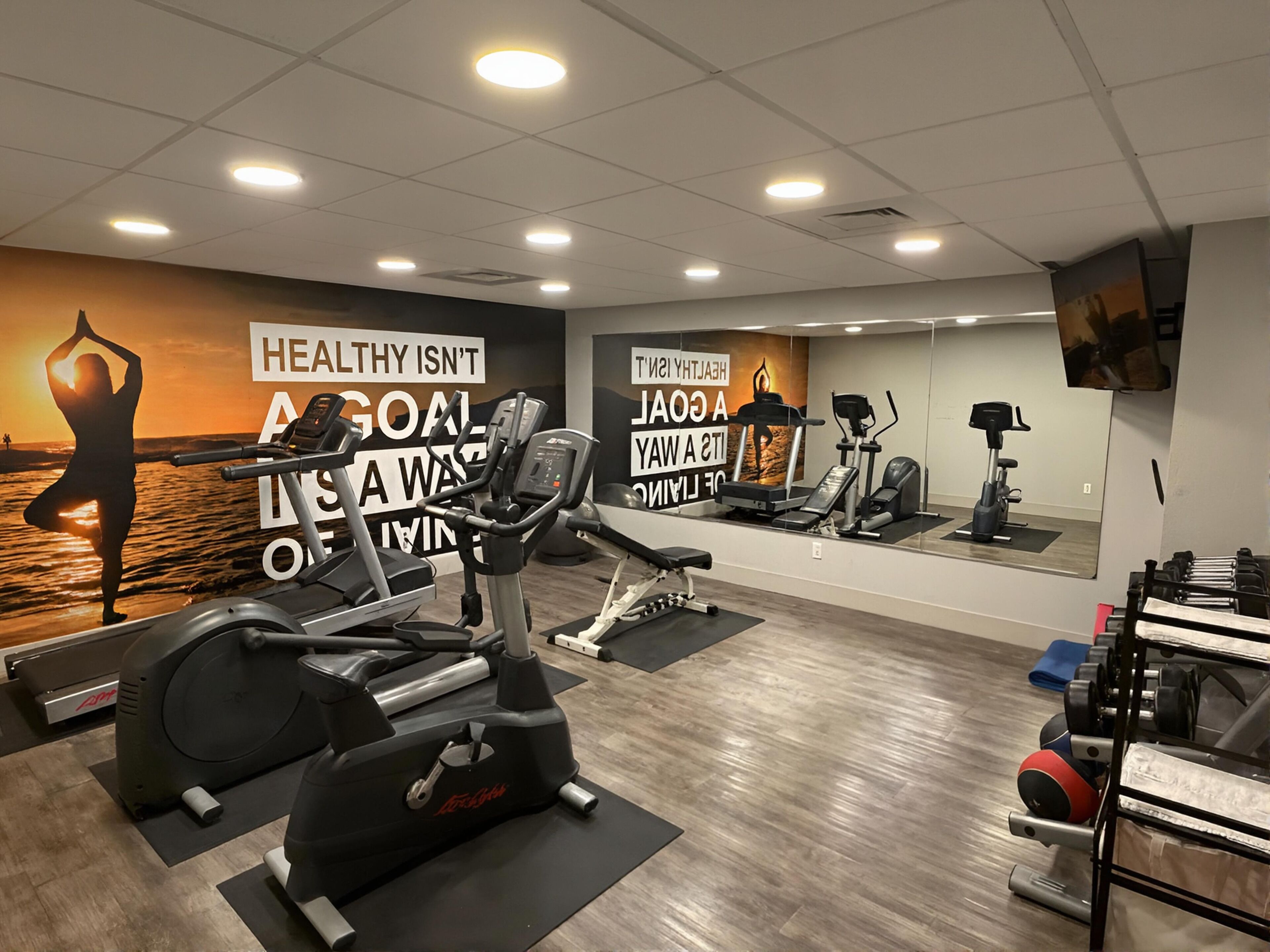 A gym with exercise equipment, a large mirror, and motivational wall art.