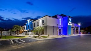 Un hotel de diseño moderno, con un llamativo letrero de 'Best Western', una entrada bien iluminada y un estacionamiento con señal de acceso para discapacitados.