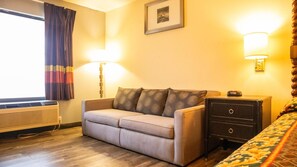 Una habitación con sofá, mesita de noche, lámpara y calentador.