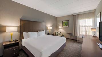 A hotel room with a large bed, bedside tables with lamps, a desk, and a television.