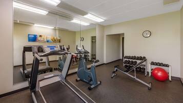 A gym with treadmills, an elliptical, dumbbells, and a red exercise ball.