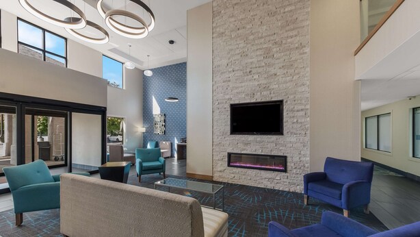 A modern lobby with a fireplace, comfortable seating, and a large TV screen. - Comfort Inn & Suites Tipp City Dayton North I-75 (Tipp City)