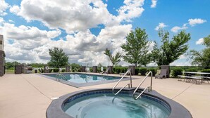 A swimming pool area with two pools, one circular and one rectangular, surrounded by a paved deck. There are lounge chairs and a picnic table in the background. - Best Western Locust Grove Inn & Suites (Locust Grove)