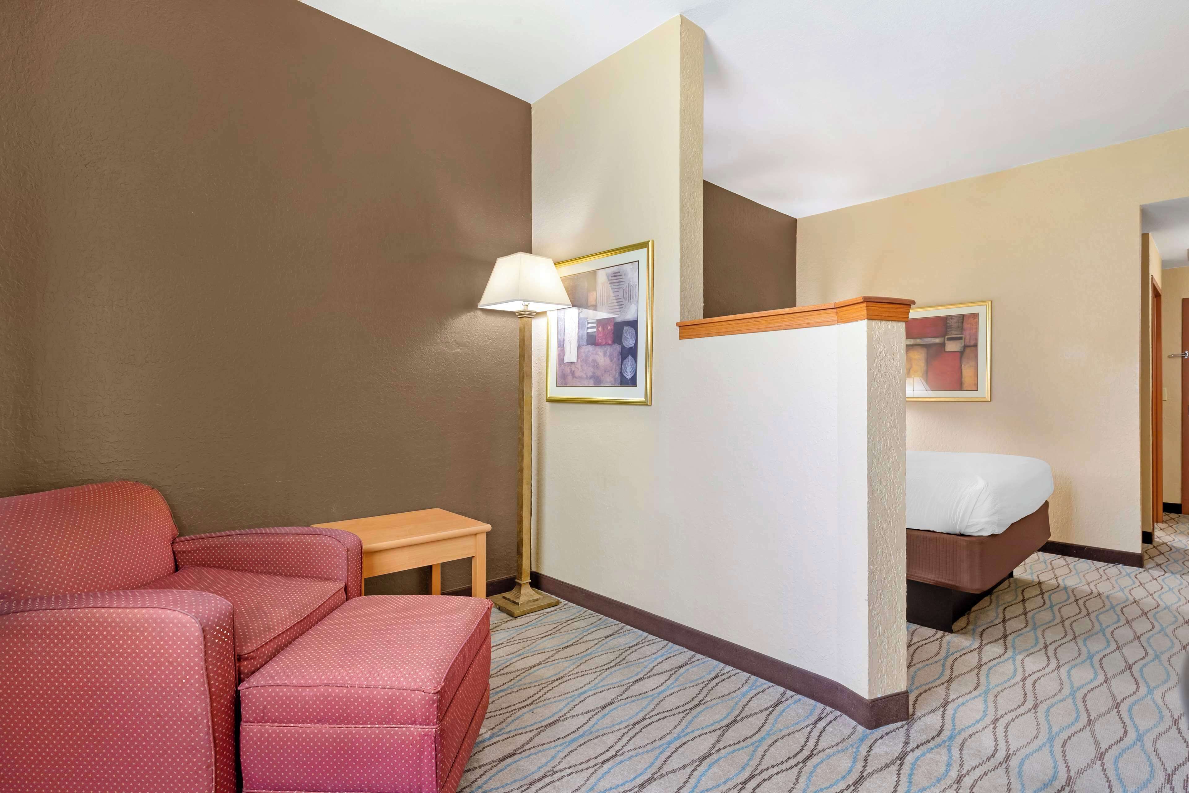 Habitación de hotel con cama, escritorio, silla y lámpara de pie.