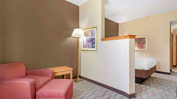 Habitación de hotel con cama, escritorio, silla y lámpara de pie.
