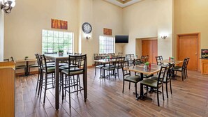 A spacious dining area with multiple tables and chairs, a clock on the wall, and large windows allowing natural light. - Best Western Locust Grove Inn & Suites (Locust Grove)
