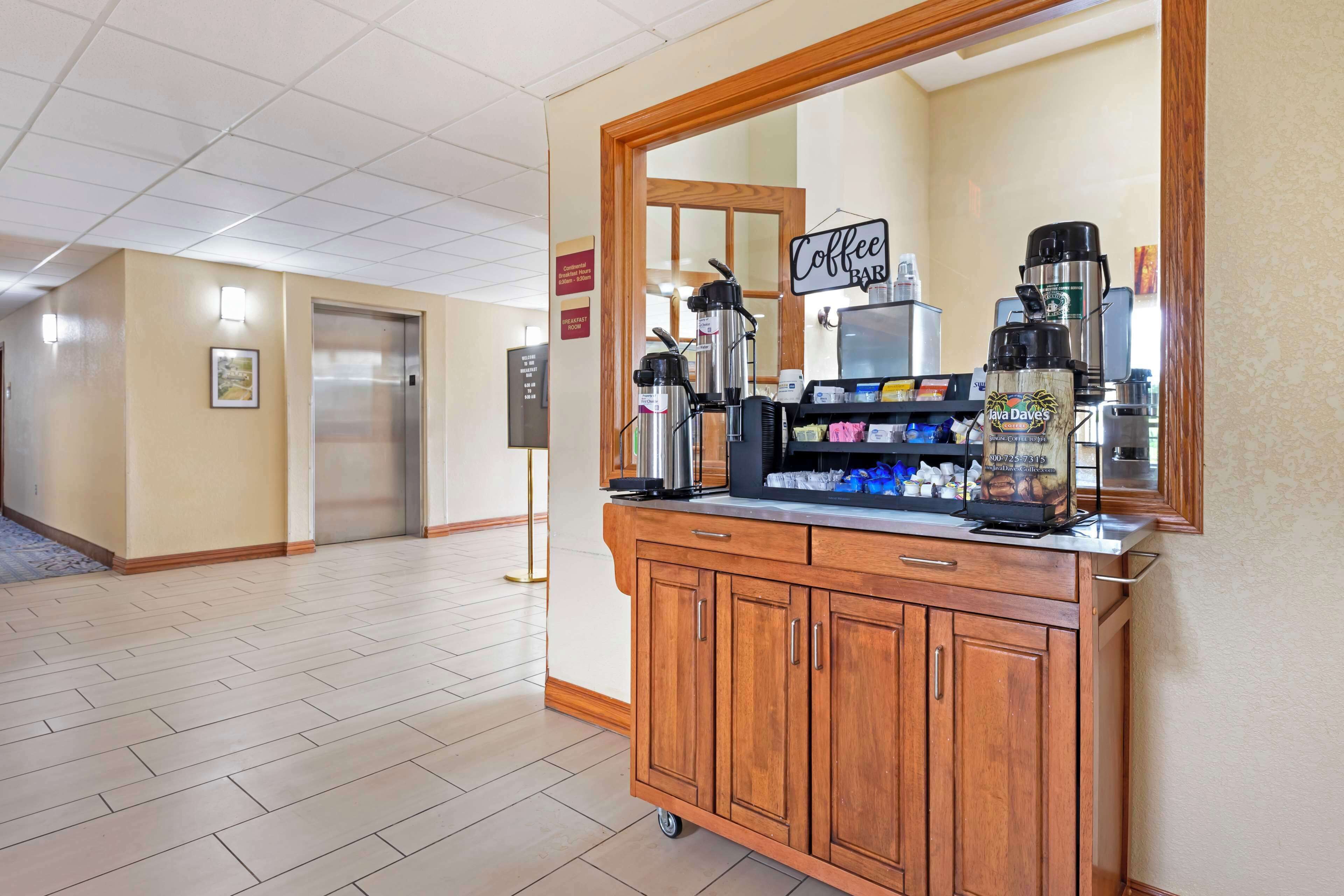 Un hall de hotel con una barra de café, un espejo, una máquina expendedora y un ascensor.