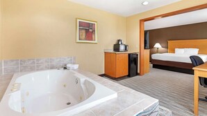 A hotel room with a large bathtub, a bed, a desk, and a microwave. - Best Western Locust Grove Inn & Suites (Locust Grove)