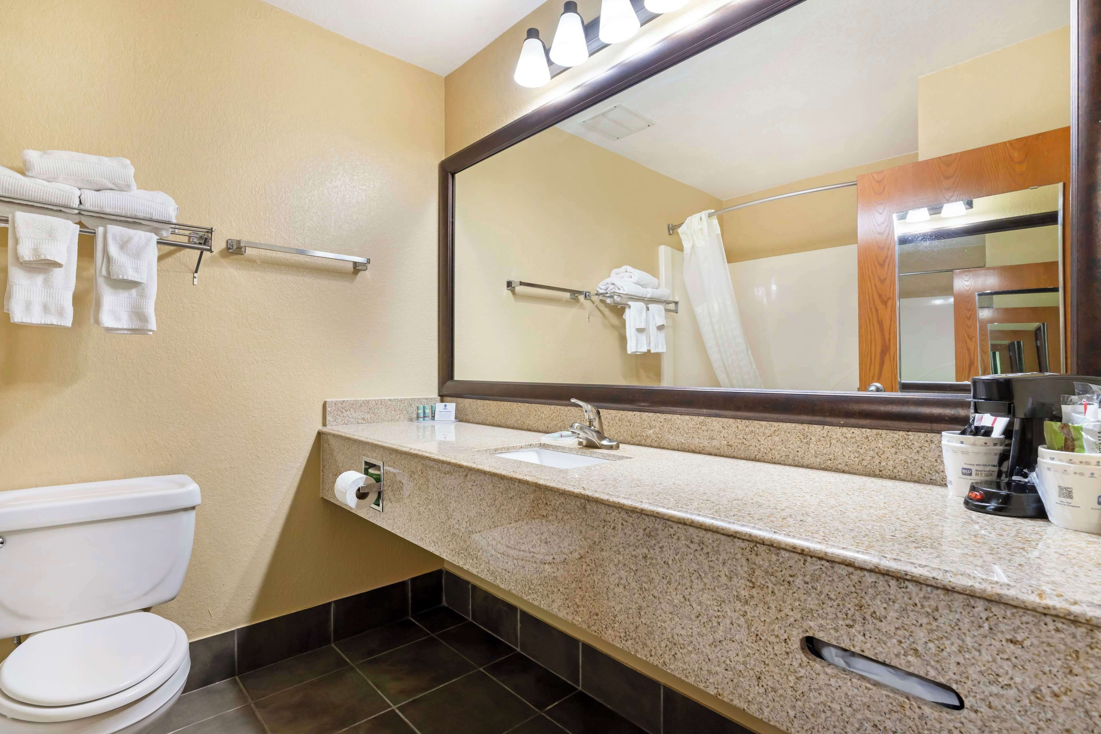 Une salle de bain d’hôtel équipée de toilettes, d’un lavabo et d’un miroir.