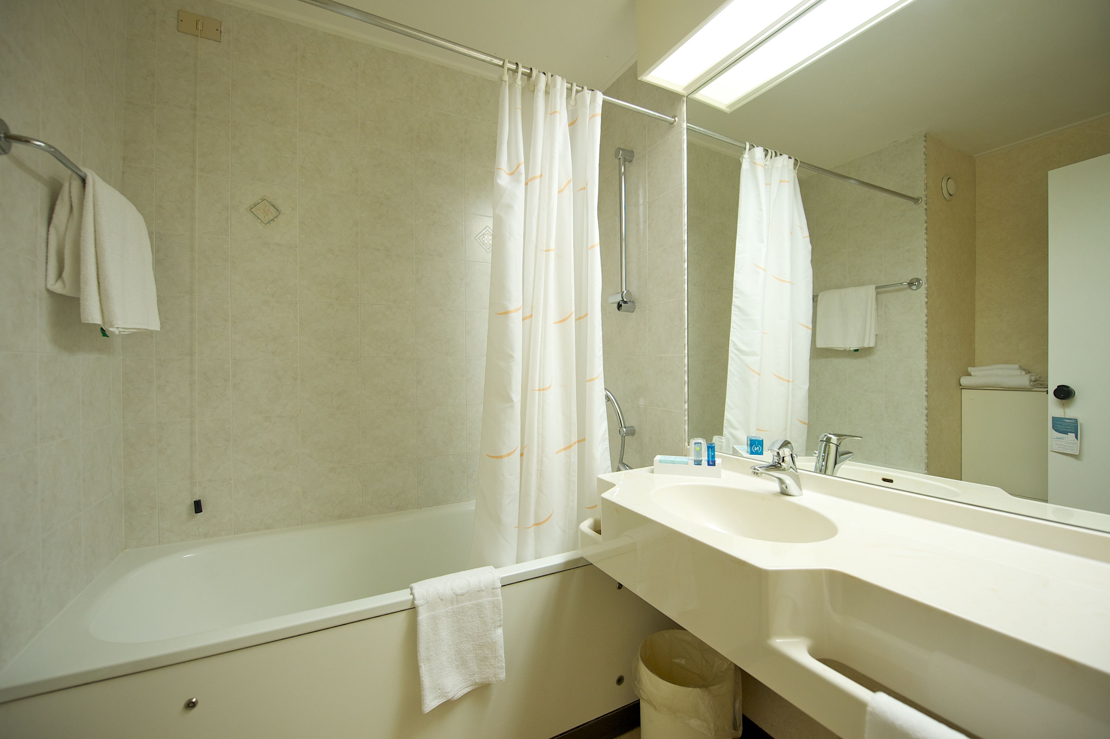 A modern bathroom with a bathtub, a sink, and a mirror.