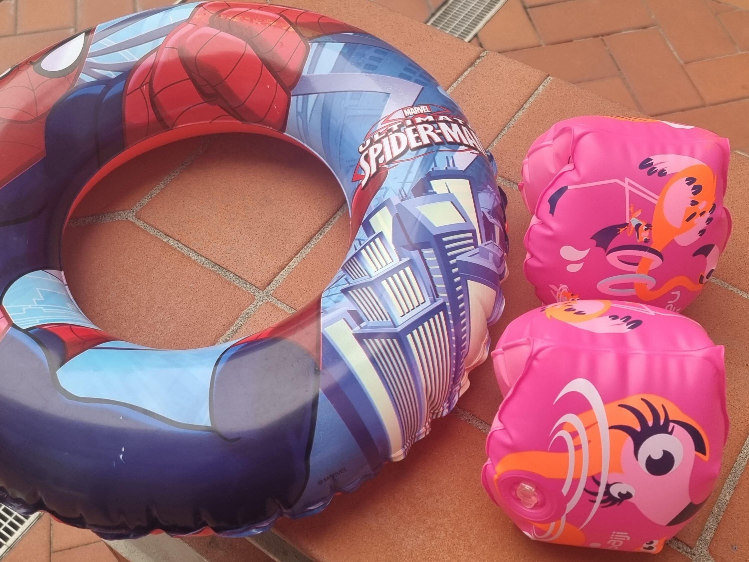 A pool float with a Spider-Man design and two pink inflatable toys.
