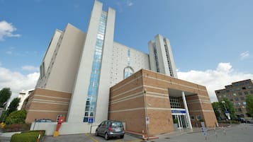 Ein modernes Gebäude mit einer markanten Eingangspartei, einem Parkplatz und einem strahlend blauen Himmel.