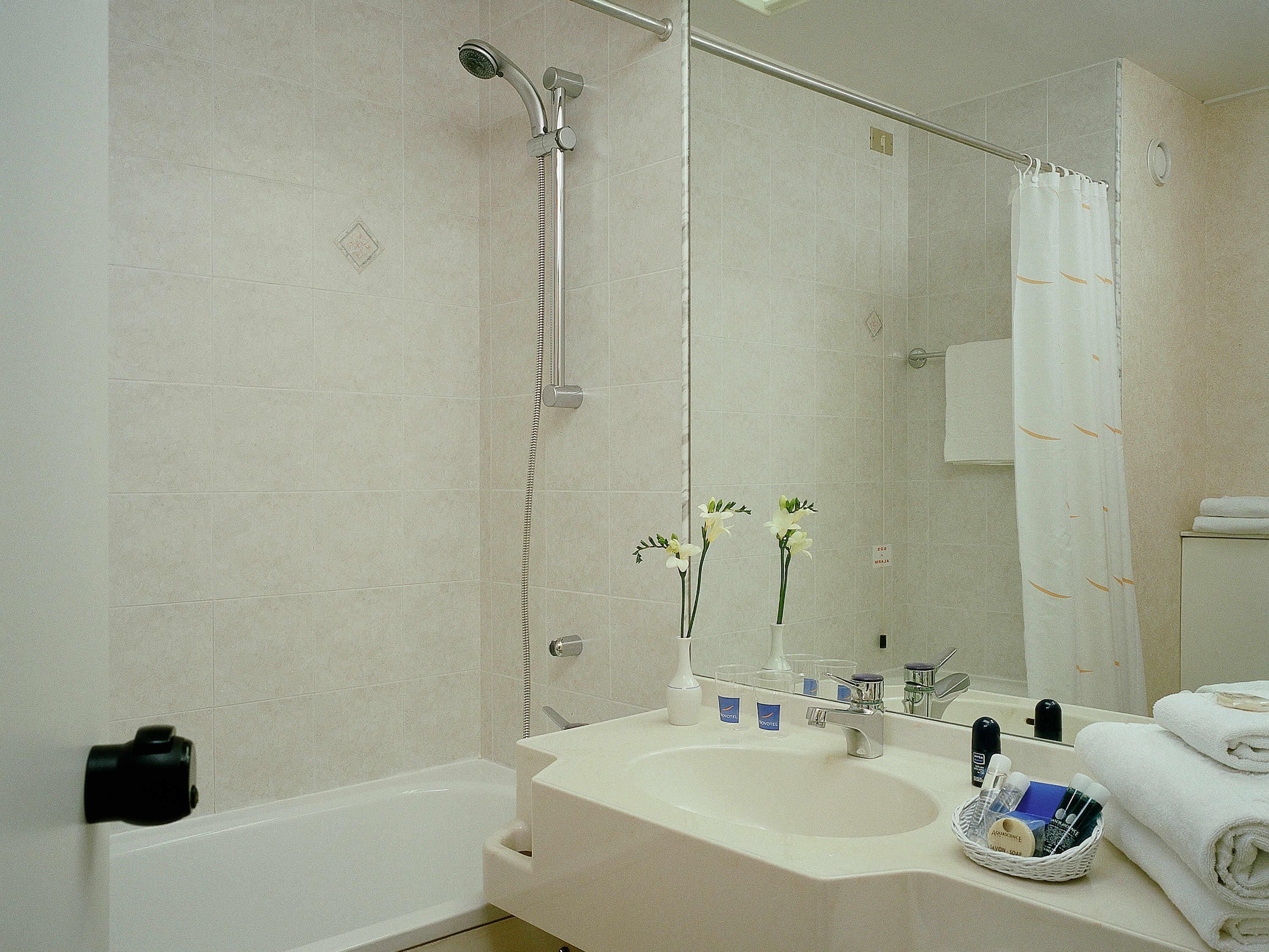 Un baño con bañera, lavabo con artículos de aseo y ducha.