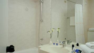Un baño con bañera, lavabo con artículos de aseo y ducha.