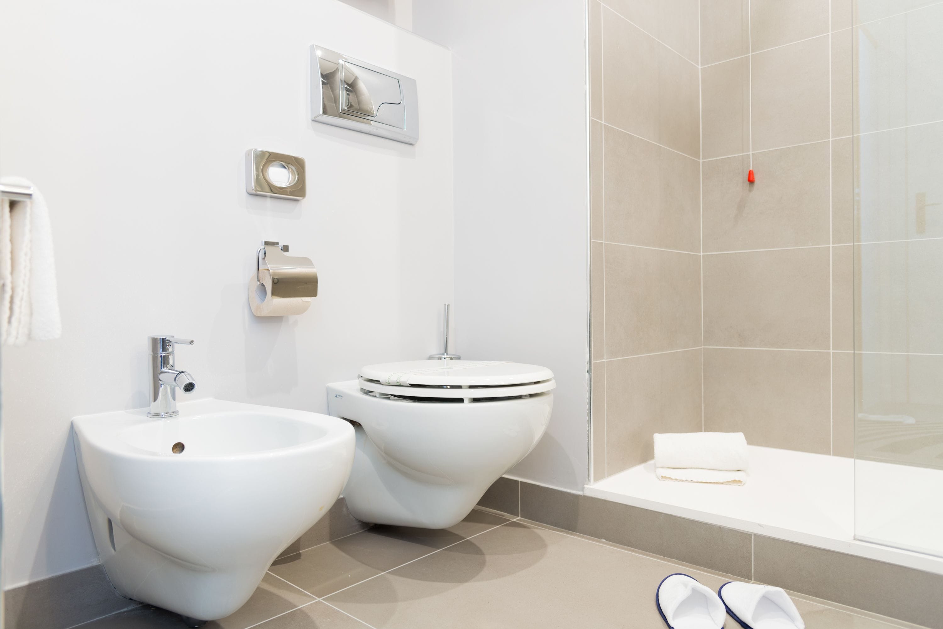 A modern bathroom with a bidet, toilet, sink, and bathtub.