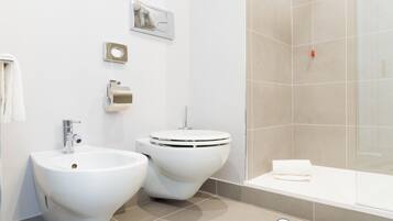 A modern bathroom with a bidet, toilet, sink, and bathtub.