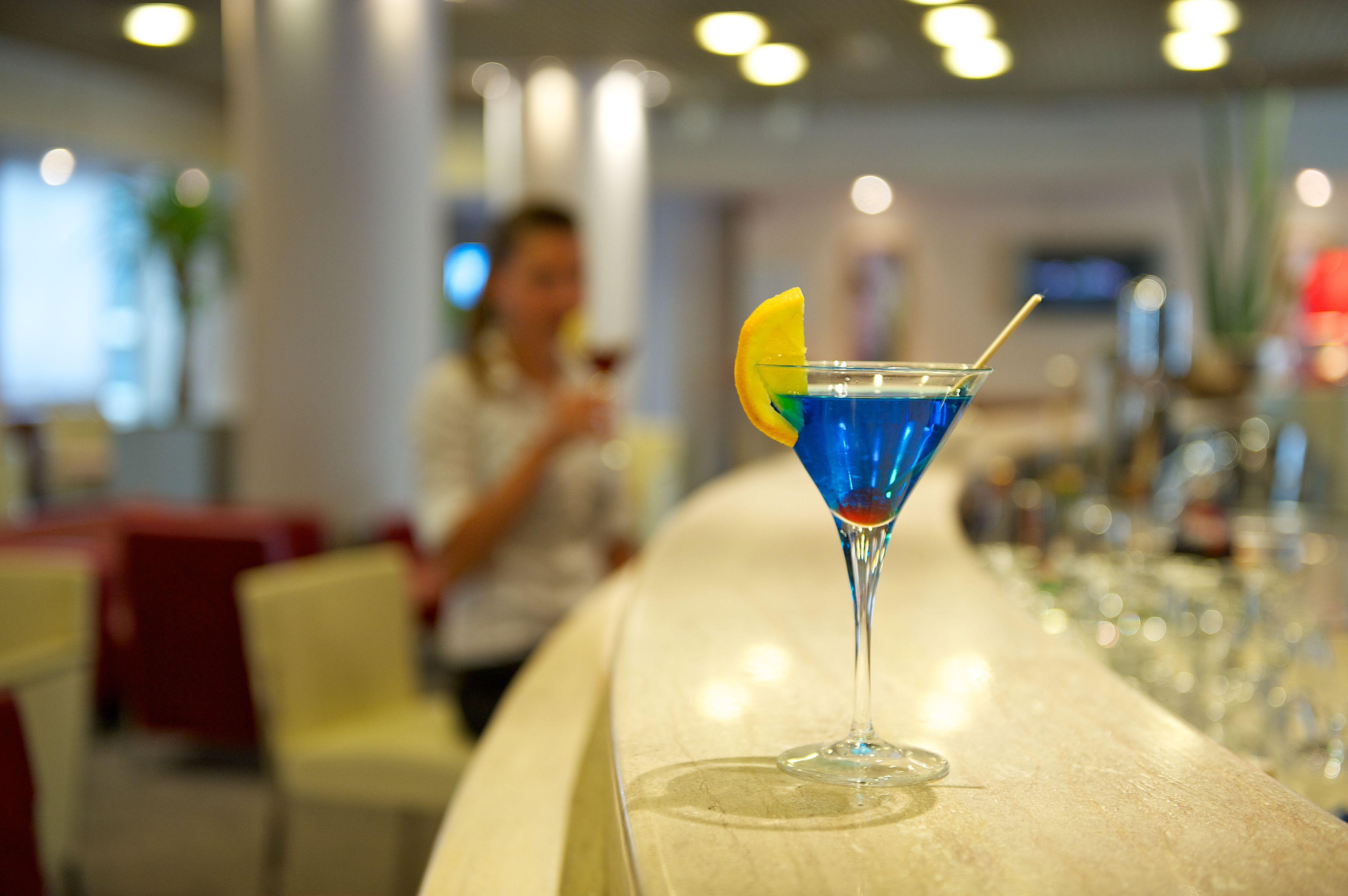 A bar area with a blue cocktail and a lemon slice garnish.