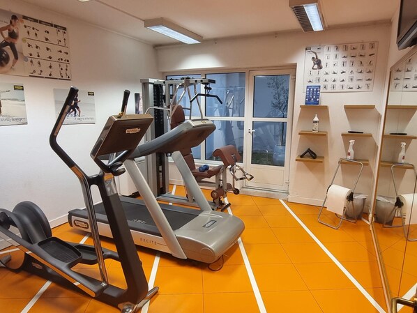 A gym with treadmills, weight machines, and a mirror.