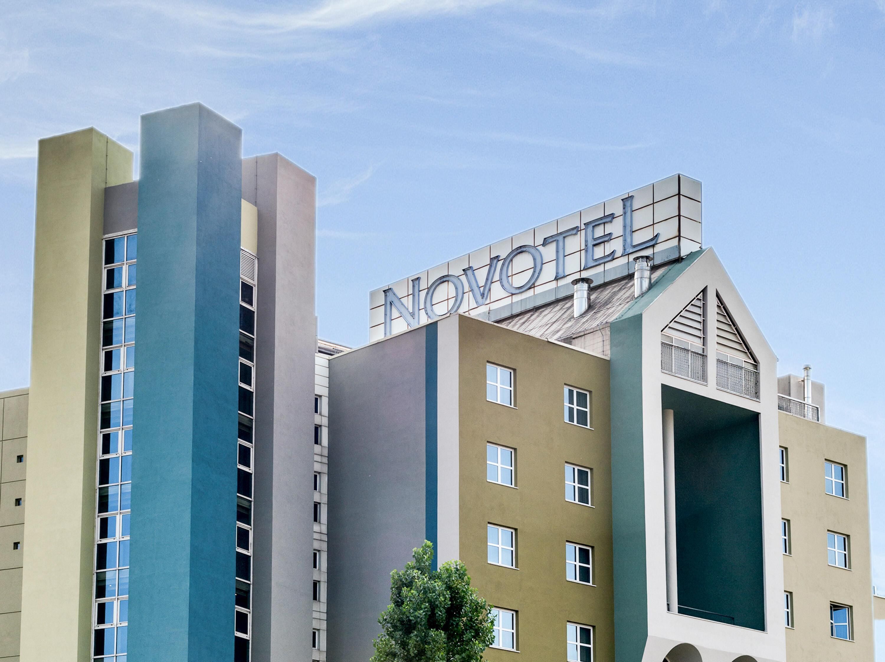 A hotel with a modern design, featuring a prominent 'NOVOTEL' sign on the top.