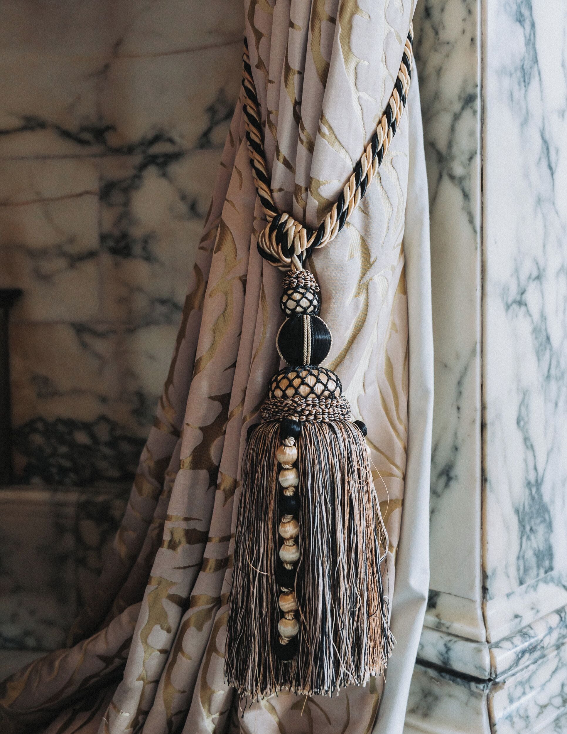 A curtain with a tassel and a braided cord.
