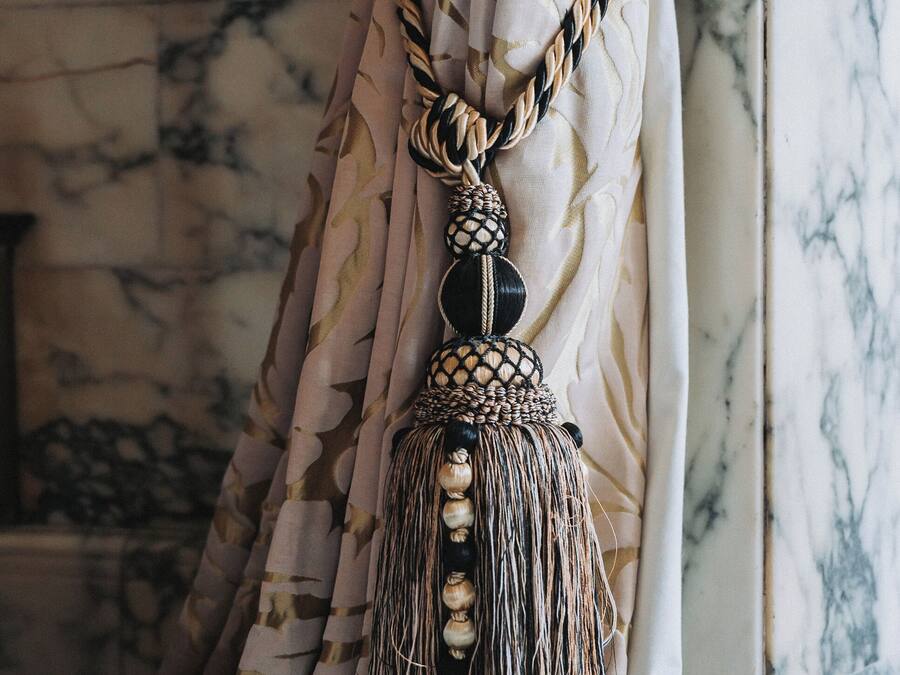 A curtain with a tassel and a braided cord.