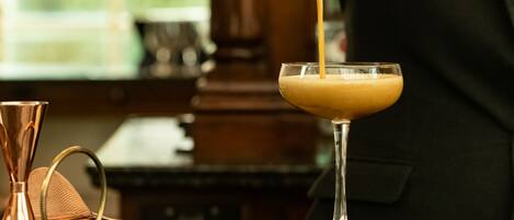 A bartender pouring a drink into a martini glass.