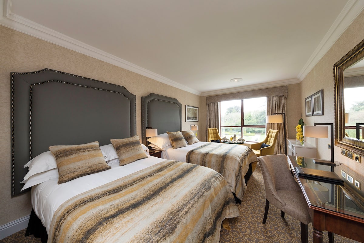 A hotel room with two beds, a desk, and a chair.